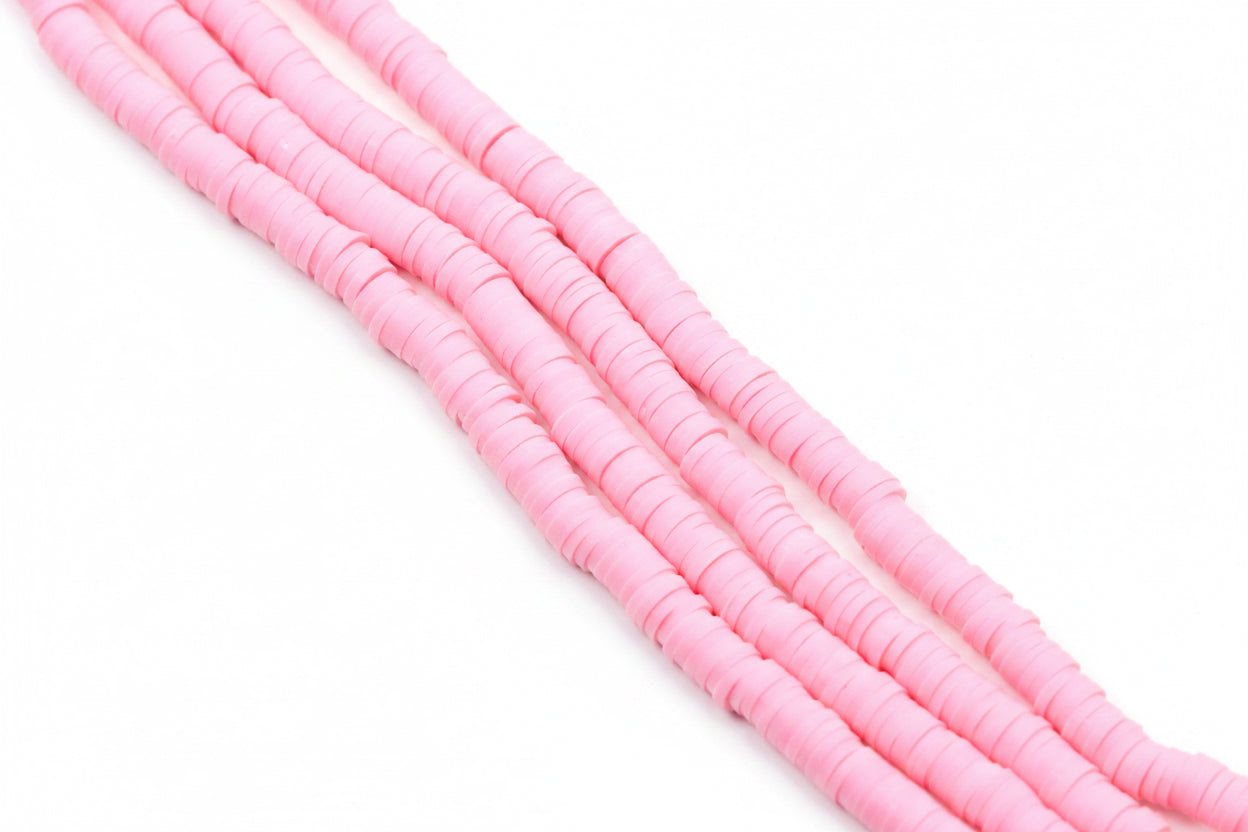 pink polymer clay disc beads arranged in diagonal strands on a plain white background.