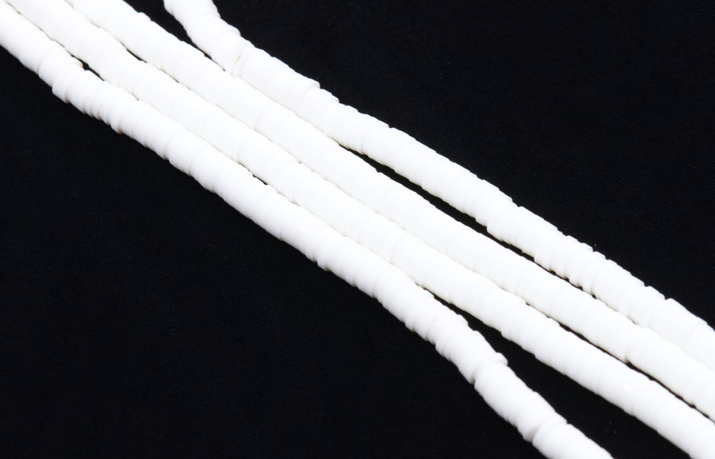 multiple strands of white polymer clay disc beads arranged diagonally on a solid black background.