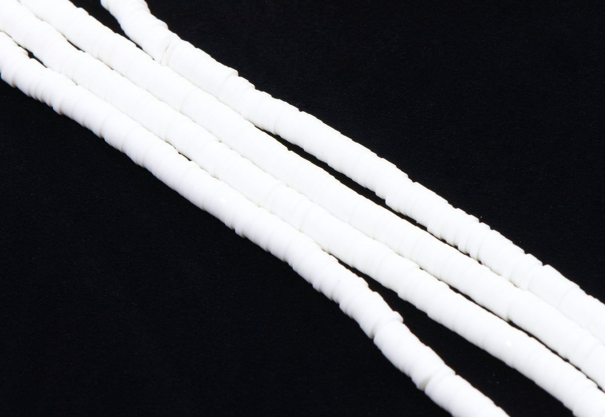 multiple strands of white polymer clay disc beads arranged diagonally on a solid black background.