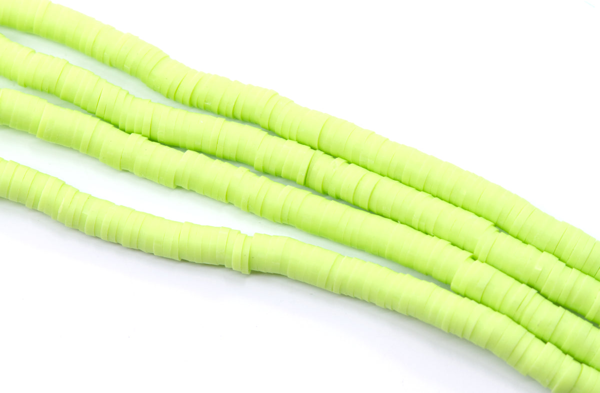 multiples strands of light green, polymer clay disc beads arranged diagonally on a plain white background.