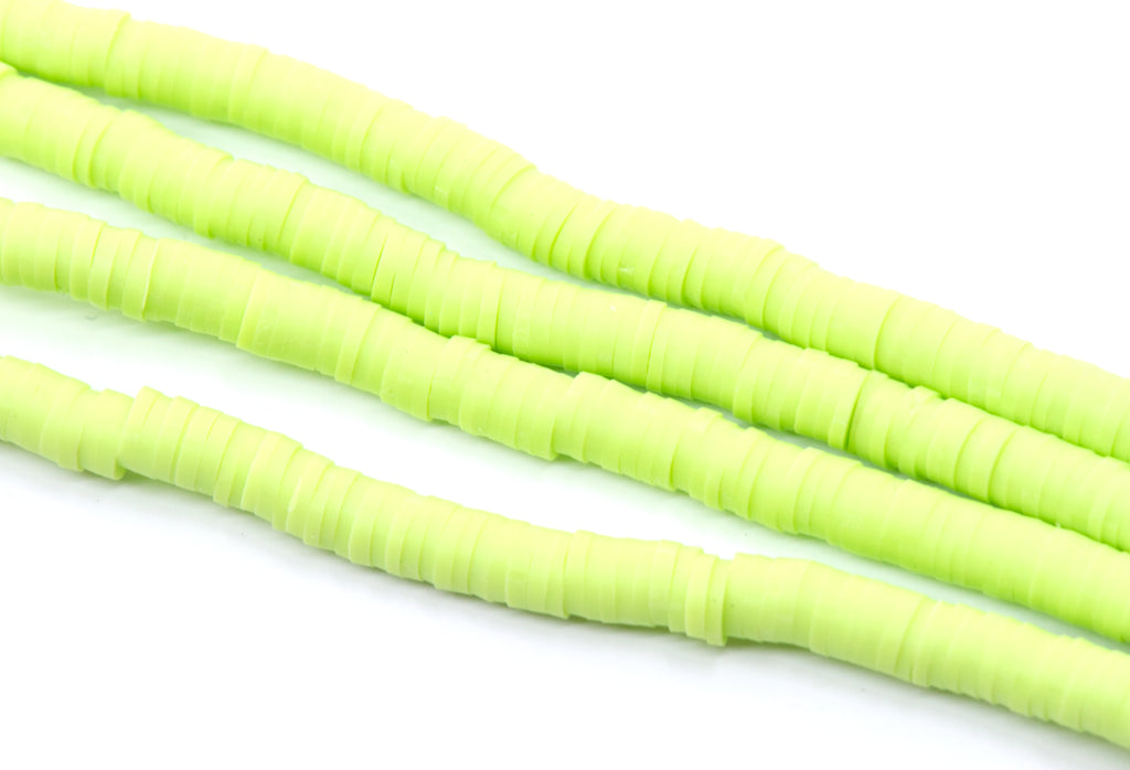 multiples strands of light green, polymer clay disc beads arranged diagonally on a plain white background.