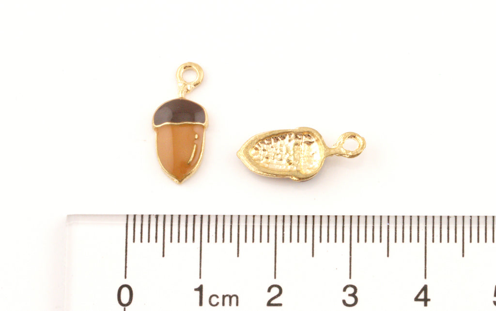 Two brown acorn gold-tone jewelry charms cm ruler on a white background.
