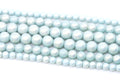 Multiple strands of light blue shimmery acrylic beads arranged diagonally on a plain white background.
