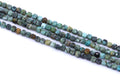 four strands of African turquoise faceted, cube gemstone beads in earthy green, blue, brown, and black marbled patterns, laid diagonally on a white background.