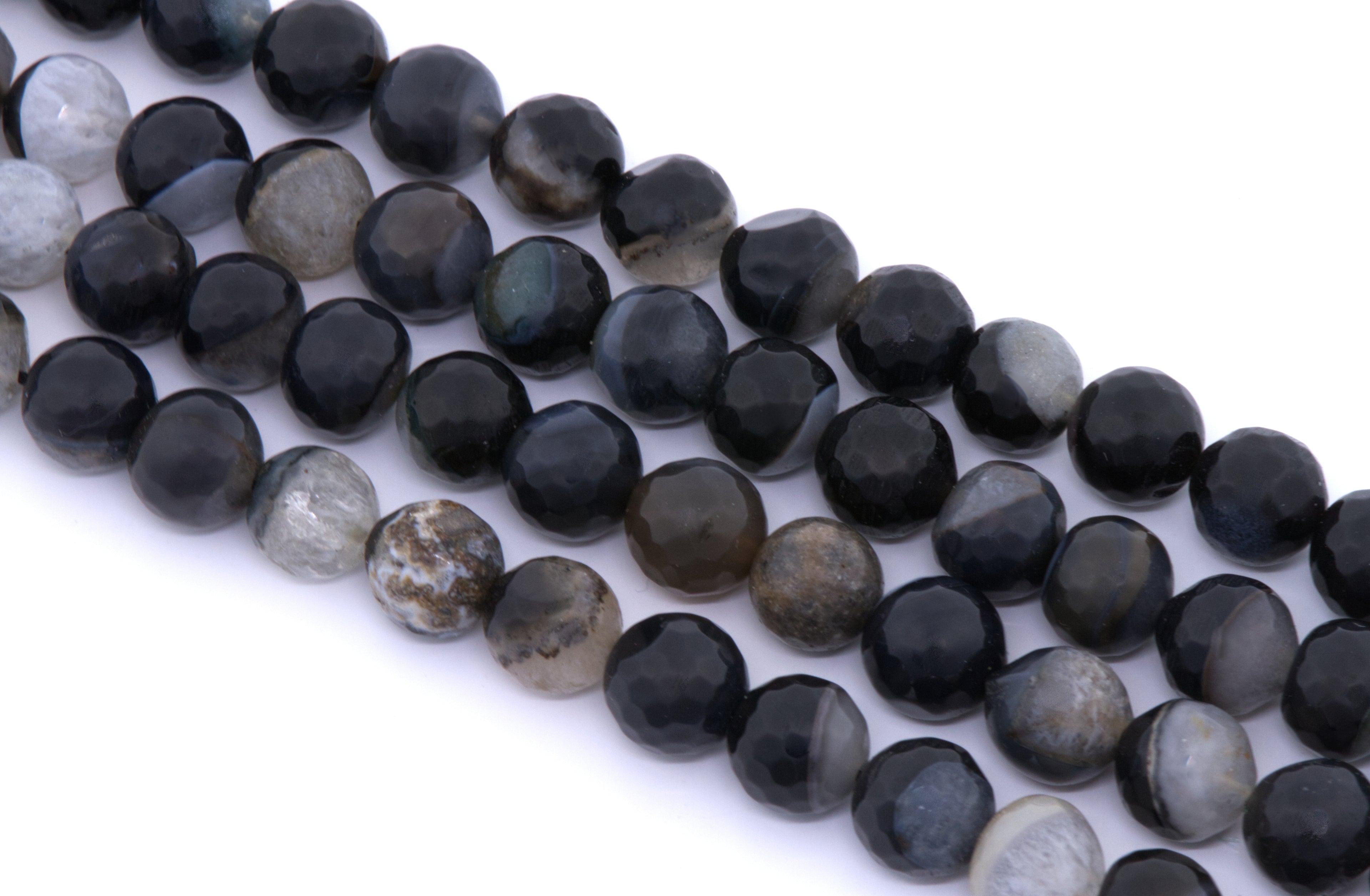 Faceted round agate beads in black and dark gray, arranged in four diagonal rows on a white background.