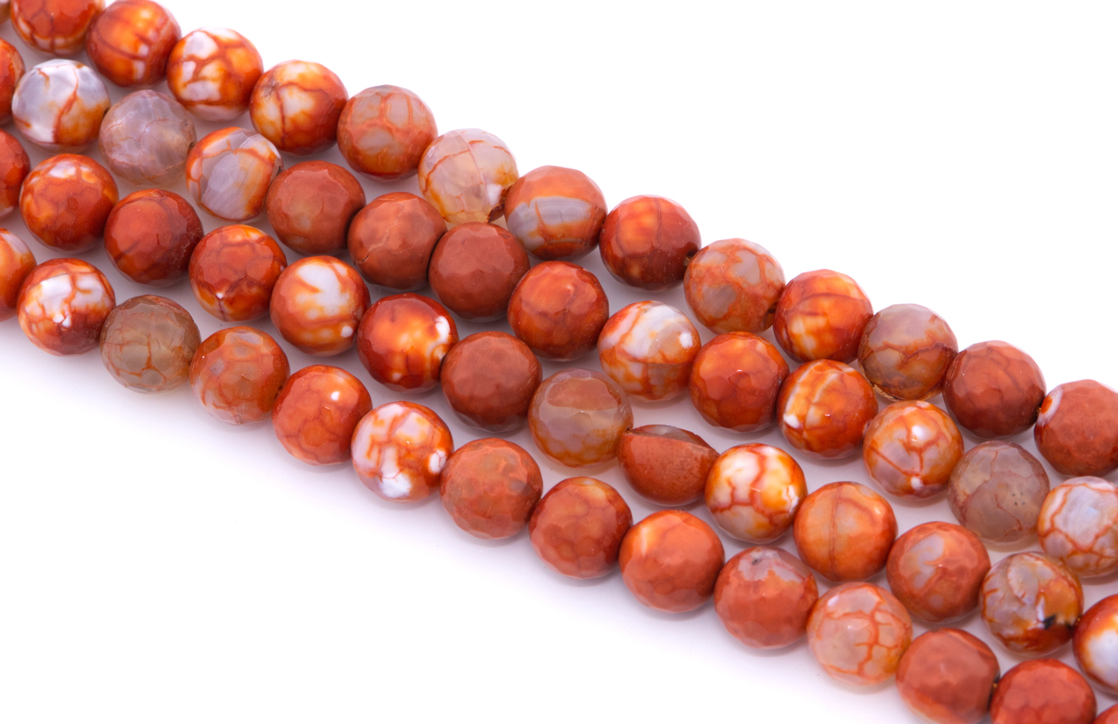 Four strands of round faceted agate beads in a mottled orange, and white agate pattern, arranged diagonally on a white background.