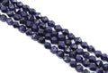 Faceted dark blue diamond cut agate beads with gold flecks, arranged in diagonal rows on a white background.