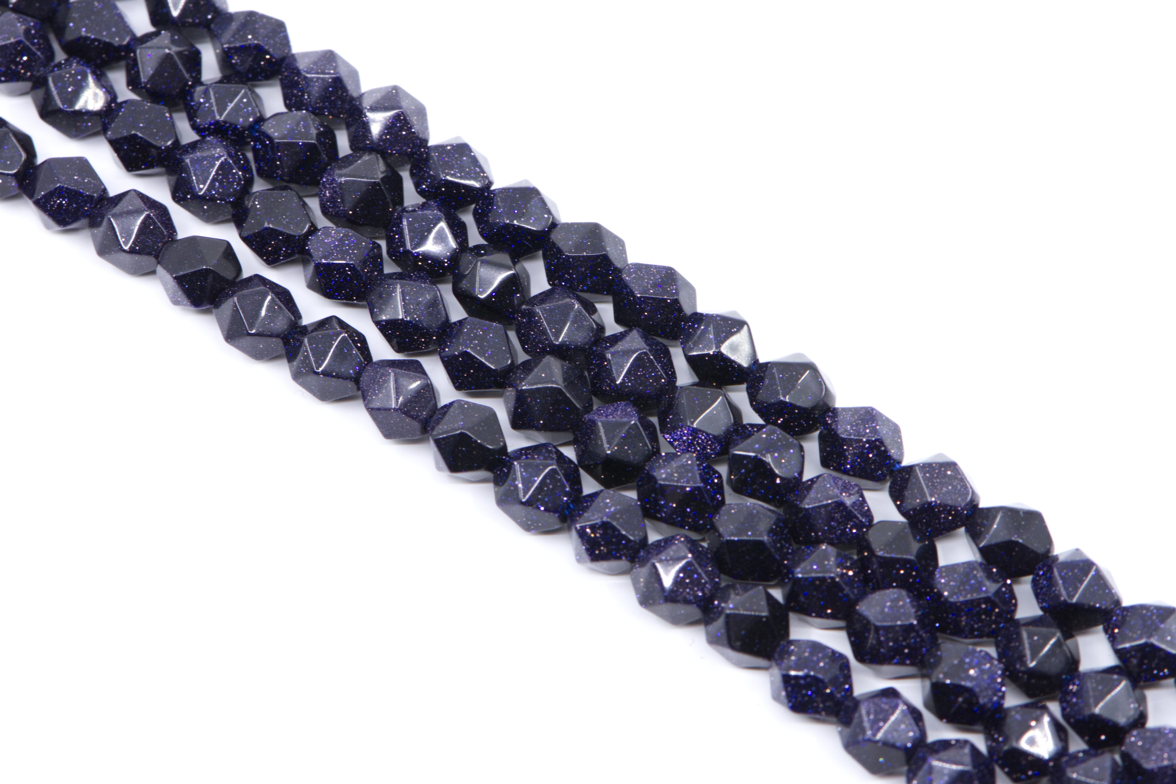 Faceted dark blue diamond cut agate beads with gold flecks, arranged in diagonal rows on a white background.