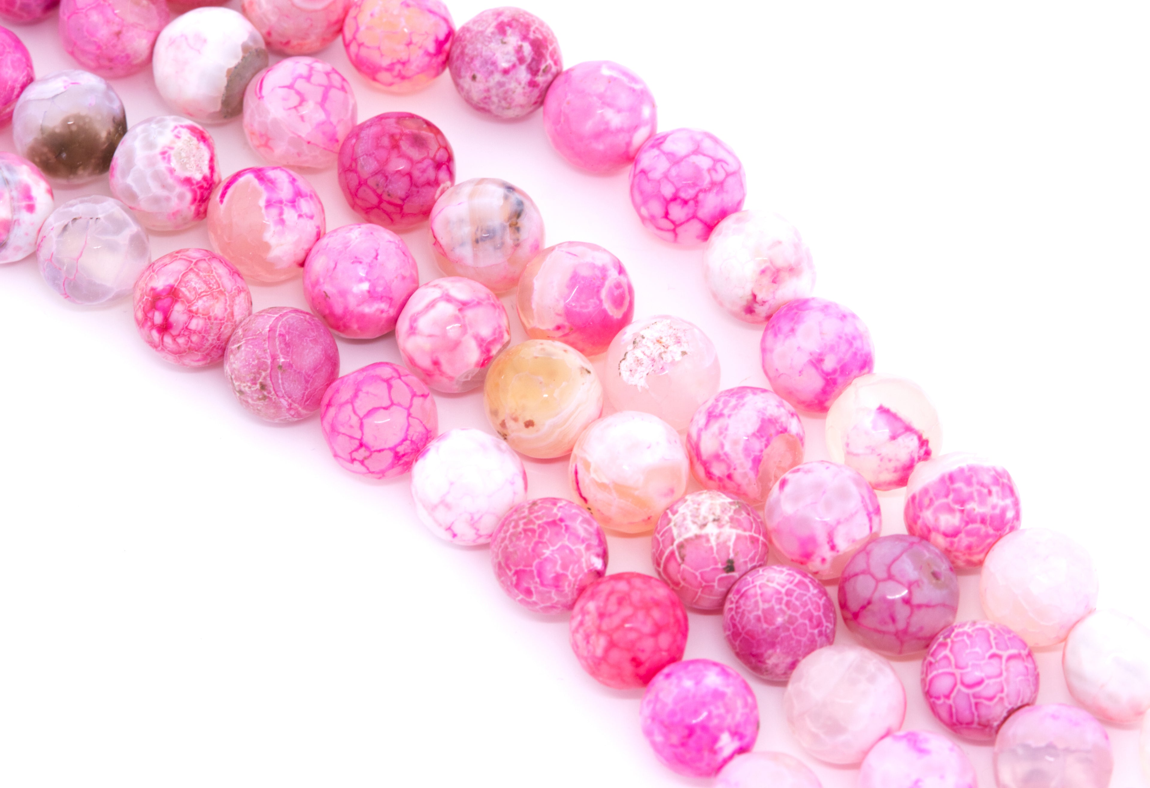 Pink faceted agate beads arranged in diagonal strands on a white background.