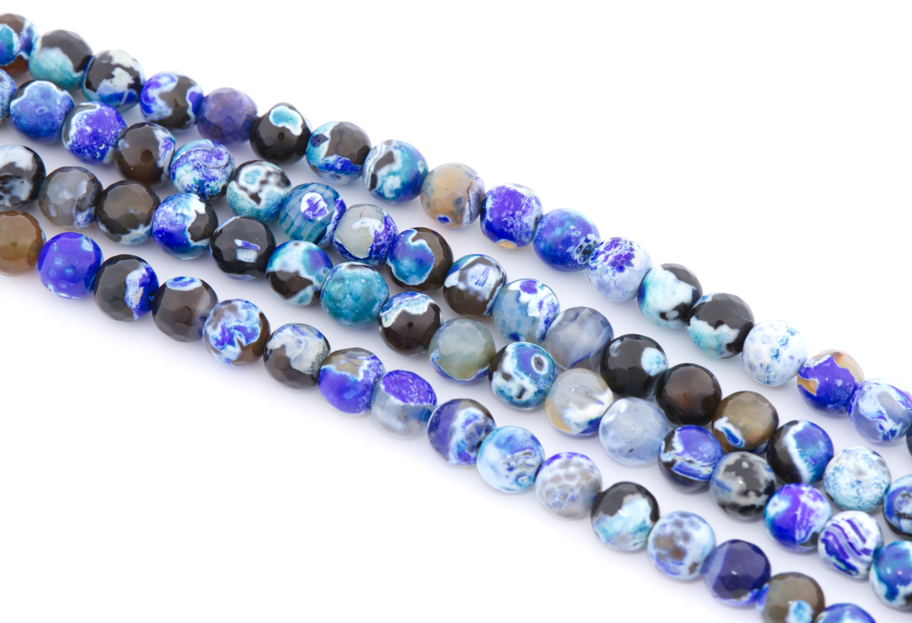 Multiple strands of faceted agate beads in shades of blue,  black, and white  arranged diagonally on a plain white background.