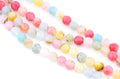 Multicolor round faceted agate beads in pink, yellow, blue, white, and gray, arranged in diagonal rows on a white background.