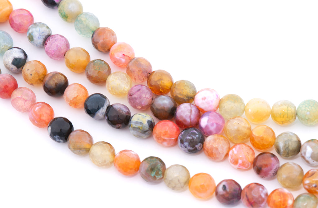 Multicolor round faceted agate beads in pink, orange, yellow and black arranged in diagonal strands on a white background.