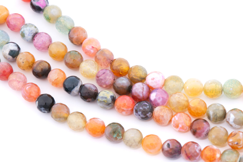 Multicolor round faceted agate beads in pink, orange, yellow and black arranged in diagonal strands on a white background.