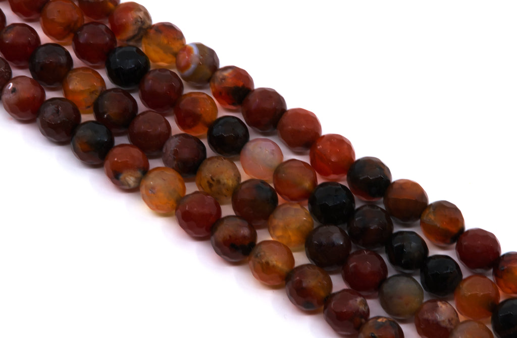 Faceted round beads in a mix of translucent amber, deep red, and dark black-brown tones, arranged diagonally on a plain white background.