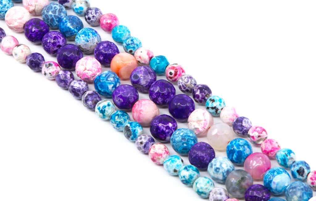 Multiple strands of round faceted agate beads in assorted colors including purple, blue, pink and white, arranged diagonally on a white background.
