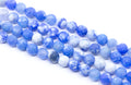 Multiple strands of round blue and white faceted agate beads arranged diagonally on a clean white background.