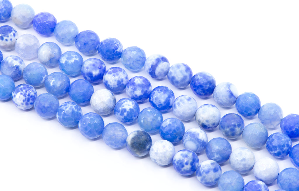 Multiple strands of round blue and white faceted agate beads arranged diagonally on a clean white background.