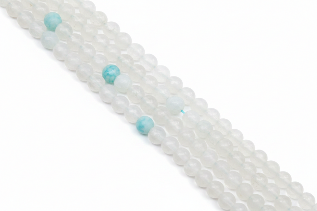 A close-up diagonal view of multiple strands of round gray beads with a few light blue marbled accent beads, photographed on a clean white background.