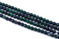 Faceted round gemstone beads in green and dark blue agate, arranged in four strands on a white background.