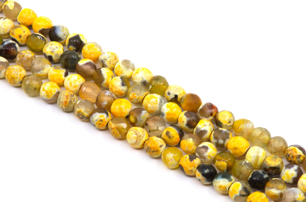 Four diagonal strand of polished round gemstone beads in golden orange and black on a white background.