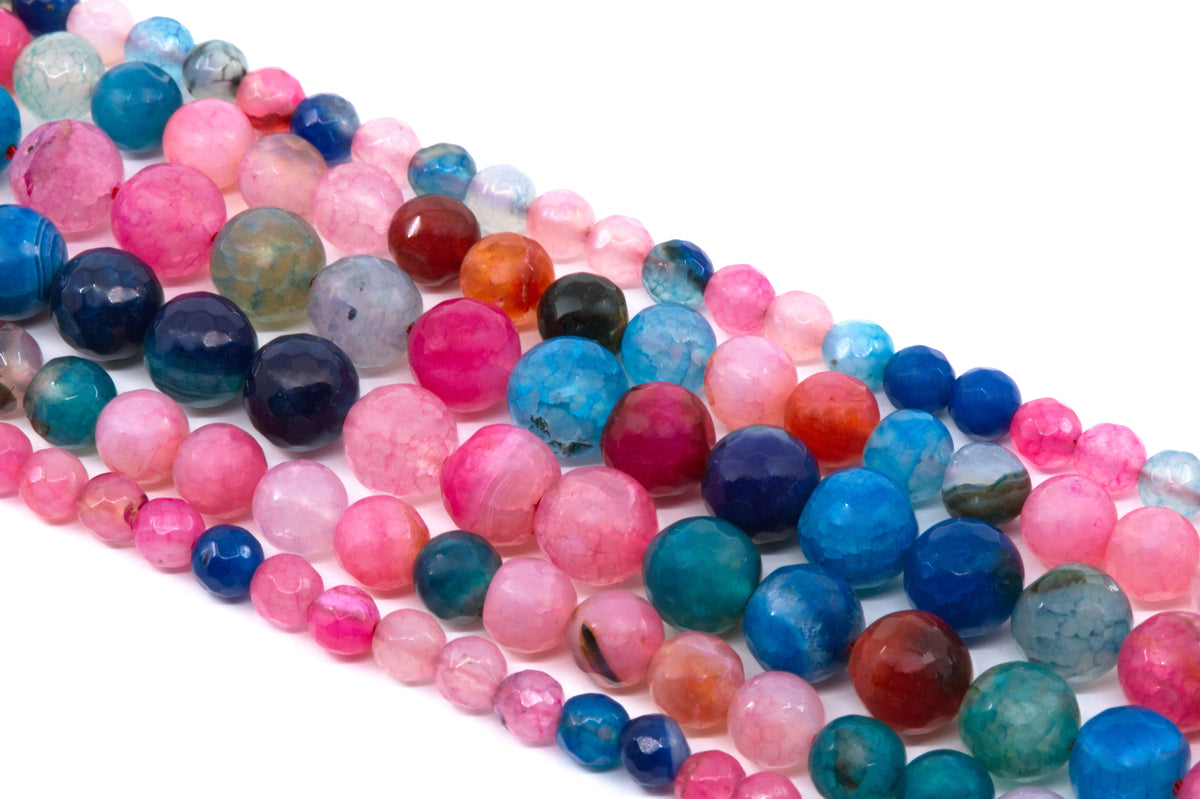 Multiple strands of faceted round agate beads in assorted colors, including pink and blue  arranged diagonally on a white background.