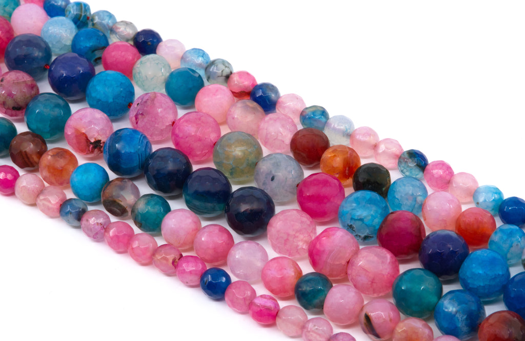 Multiple strands of faceted round agate beads in assorted colors, including pink and blue  arranged diagonally on a white background.