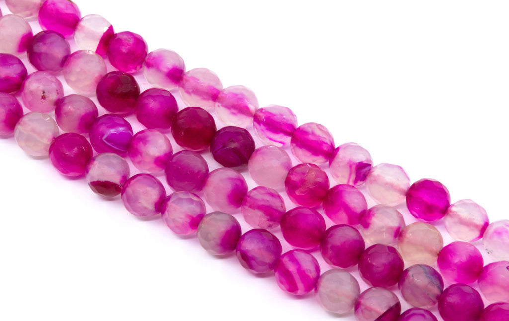 Faceted round agate beads in a marbled mix of vibrant magenta pink,  and soft translucent pink, arranged diagonally on a white background.