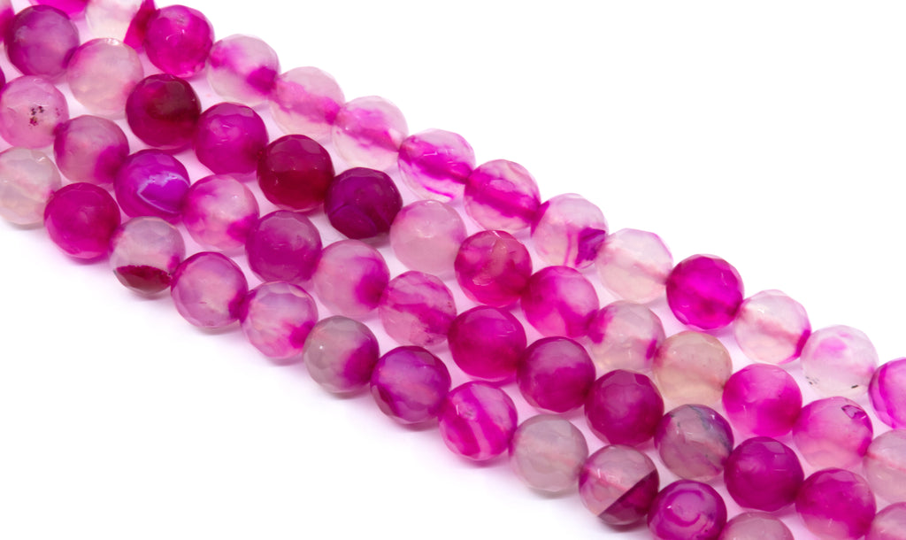 Faceted round agate beads in a marbled mix of vibrant magenta pink,  and soft translucent pink, arranged diagonally on a white background.