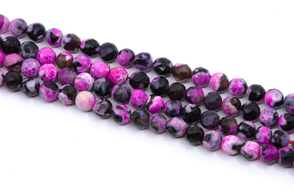 four strands of round faceted agate beads in pink and black, arranged diagonally on a plain white background.