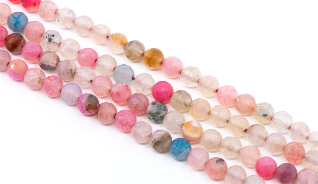 Multiple strands of polished round agate beads in assorted pastel and earthy colors, including pink, peach, blue, purple, brown, and smoky gray, arranged diagonally on a white background.