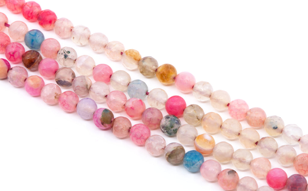Multiple strands of polished round agate beads in assorted pastel and earthy colors, including pink, peach, blue, purple, brown, and smoky gray, arranged diagonally on a white background.