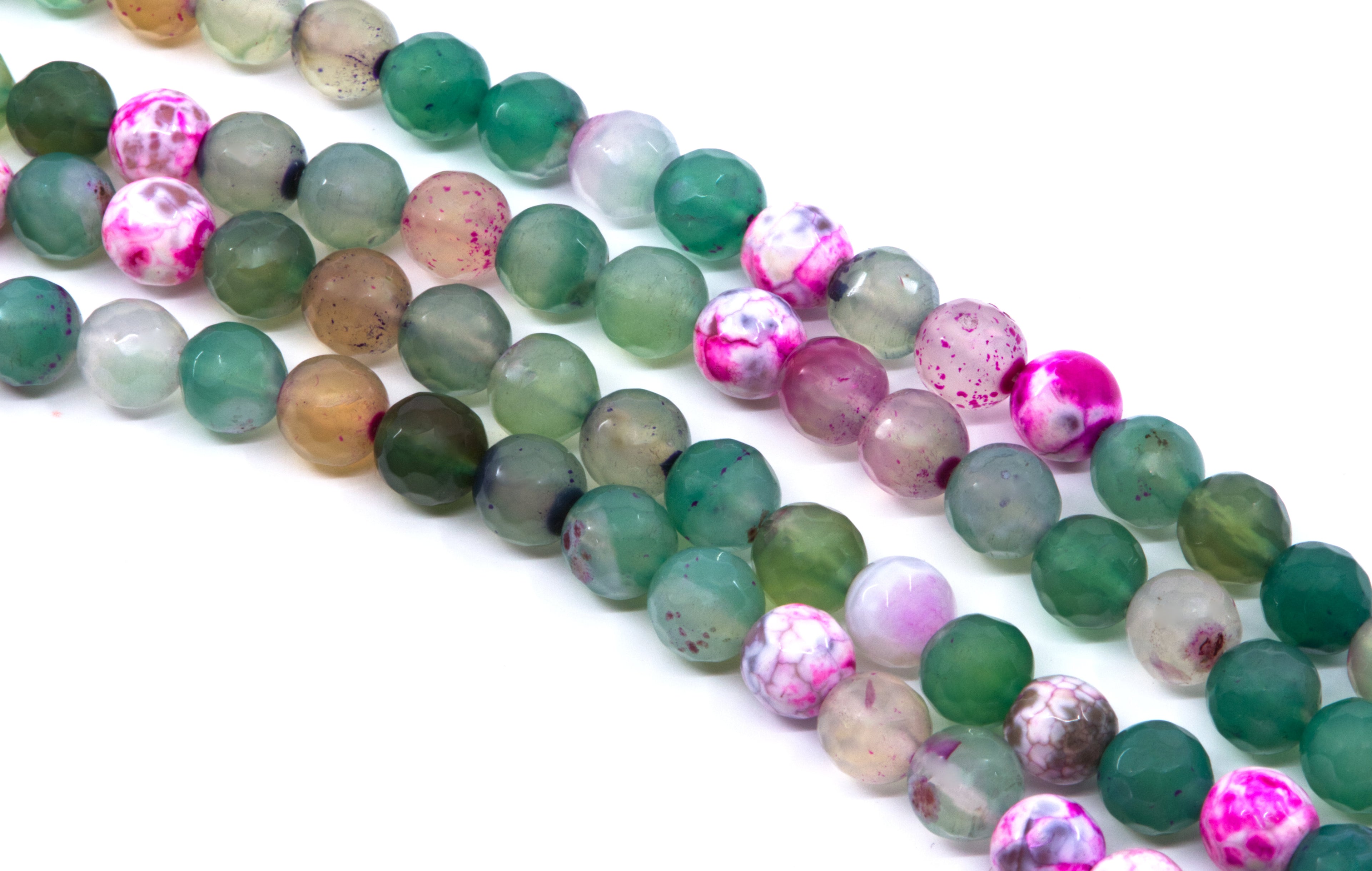 four strands of round agate beads in various colors and patterns, including green, pink, brown, and marbled designs, laid out diagonally on a white background.