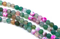 four strands of round agate beads in various colors and patterns, including green, pink, brown, and marbled designs, laid out diagonally on a white background.