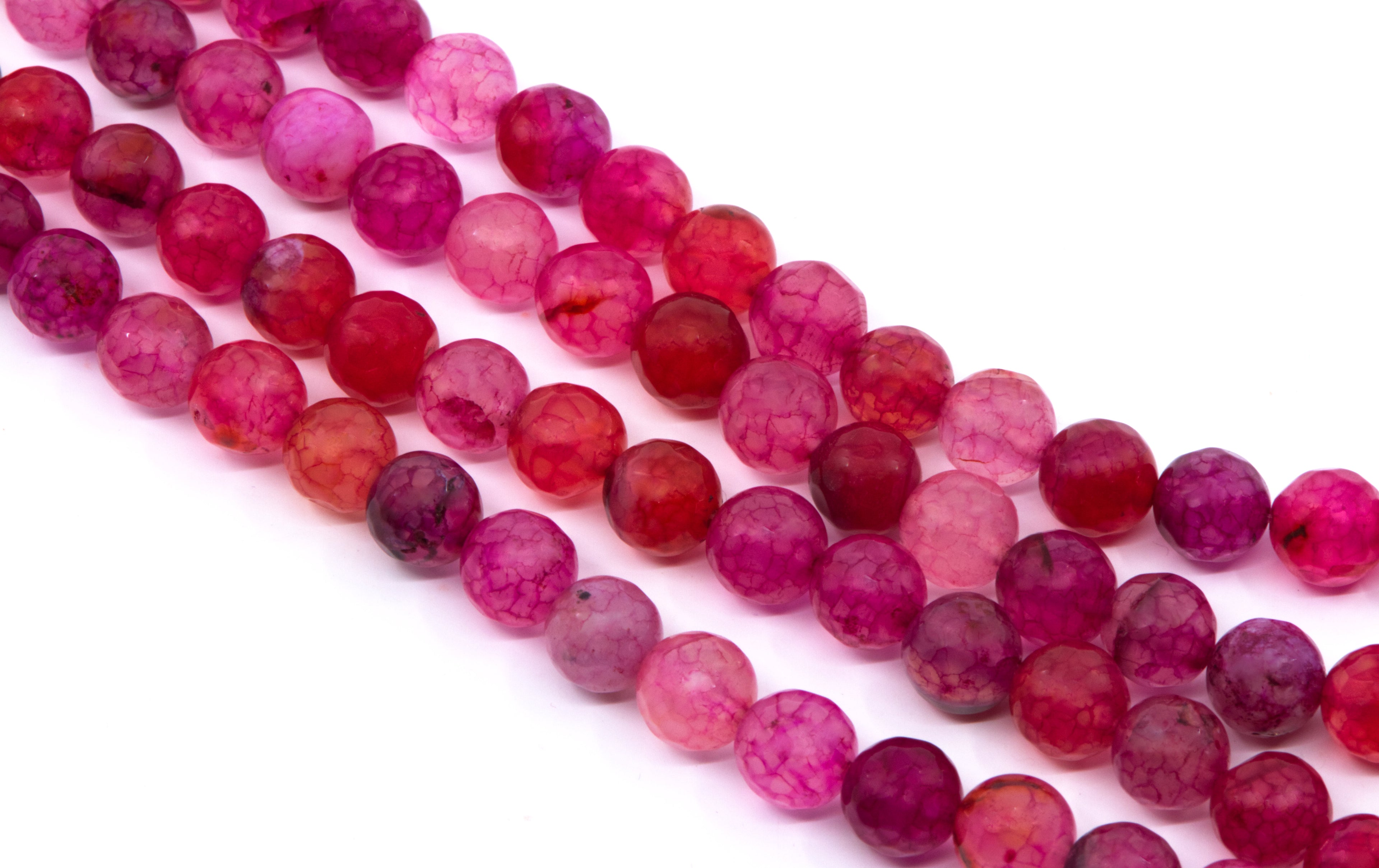 Four strands of faceted round gemstone beads in shades of pink, magenta, and red, arranged diagonally on a white background.