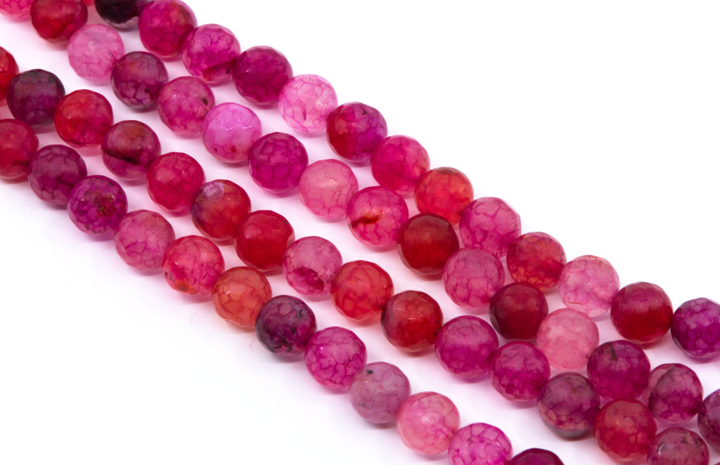 Four strands of faceted round gemstone beads in shades of pink, magenta, and red, arranged diagonally on a white background.
