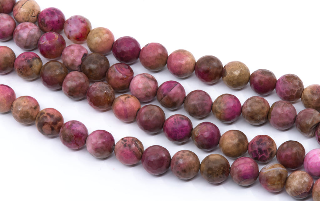 Multiple strands of polished round faceted agate beads in pinkish-red and brown , arranged diagonally on a white background.