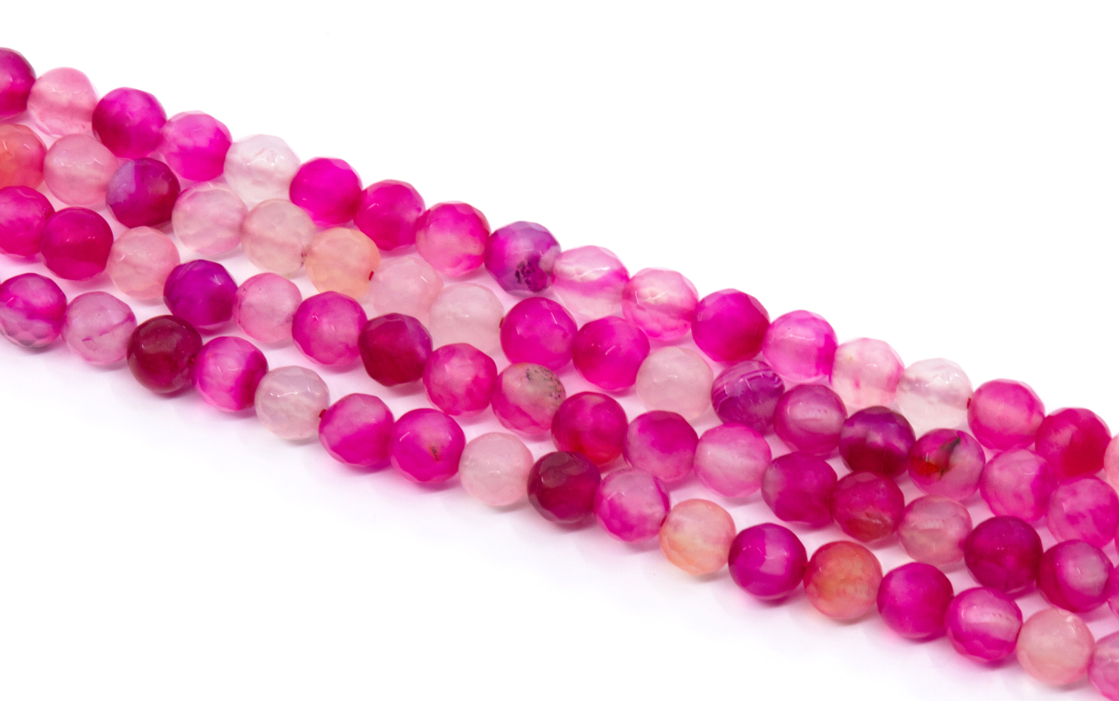 four strands of round faceted agate beads in shades of pink arranged diagonally on a white background.
