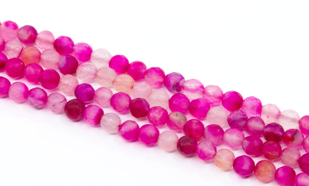four strands of round faceted agate beads in shades of pink arranged diagonally on a white background.