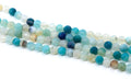 Faceted round agate beads in shades of blue, arranged in diagonal strands on a white background.
