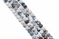 Four strands of round faceted agate beads with marbled patterns in white, gray, and blue,  arranged diagonally on a solid gray background.