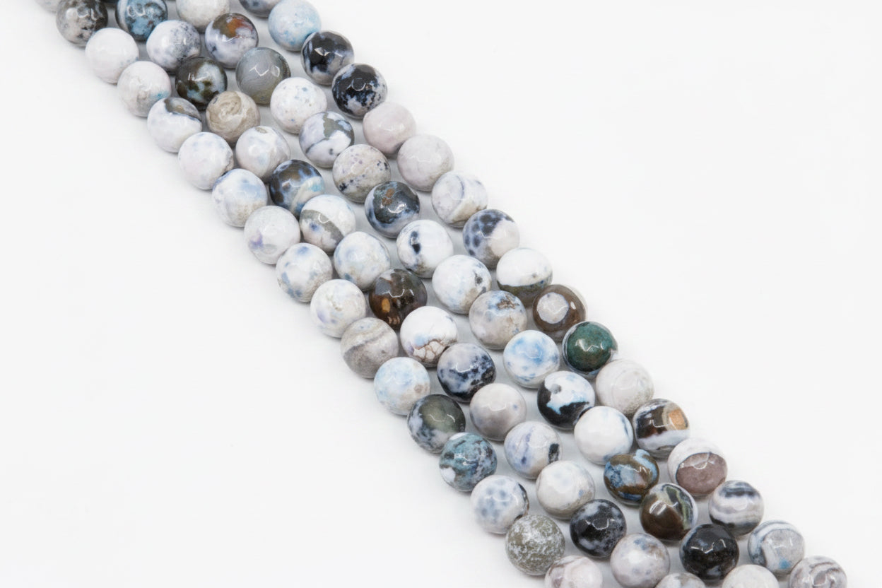 Four strands of round faceted agate beads with marbled patterns in white, gray, and blue,  arranged diagonally on a solid gray background.