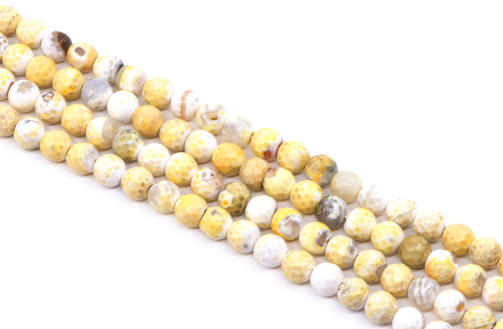four strands of faceted round agate beads, featuring a mix of yellow and white colors, arranged diagonally on a white background.