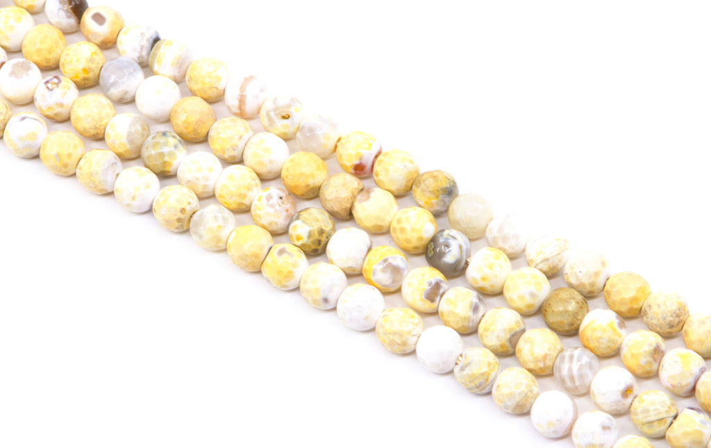 four strands of faceted round agate beads, featuring a mix of yellow and white colors, arranged diagonally on a white background.