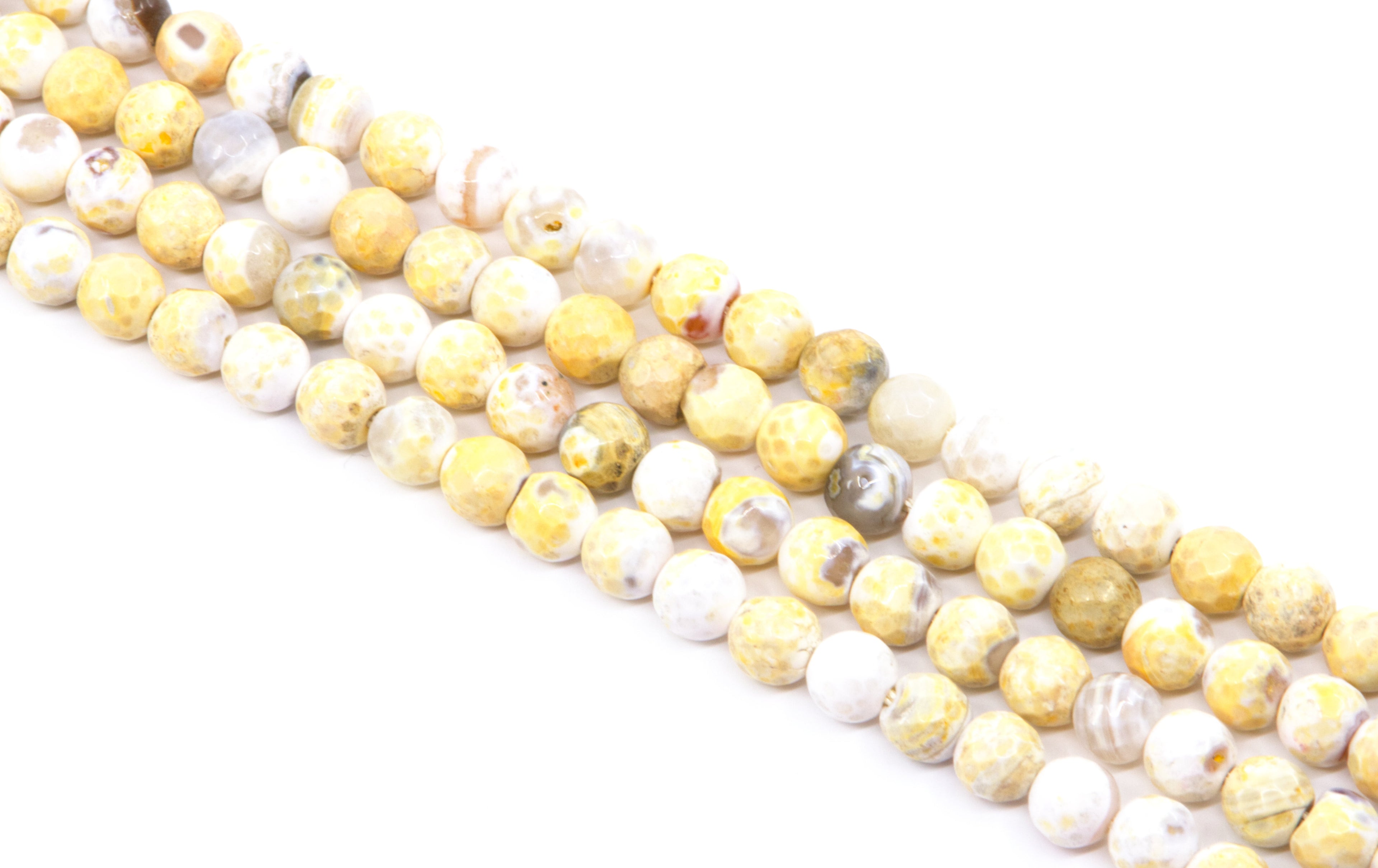 four strands of faceted round agate beads, featuring a mix of yellow and white colors, arranged diagonally on a white background.