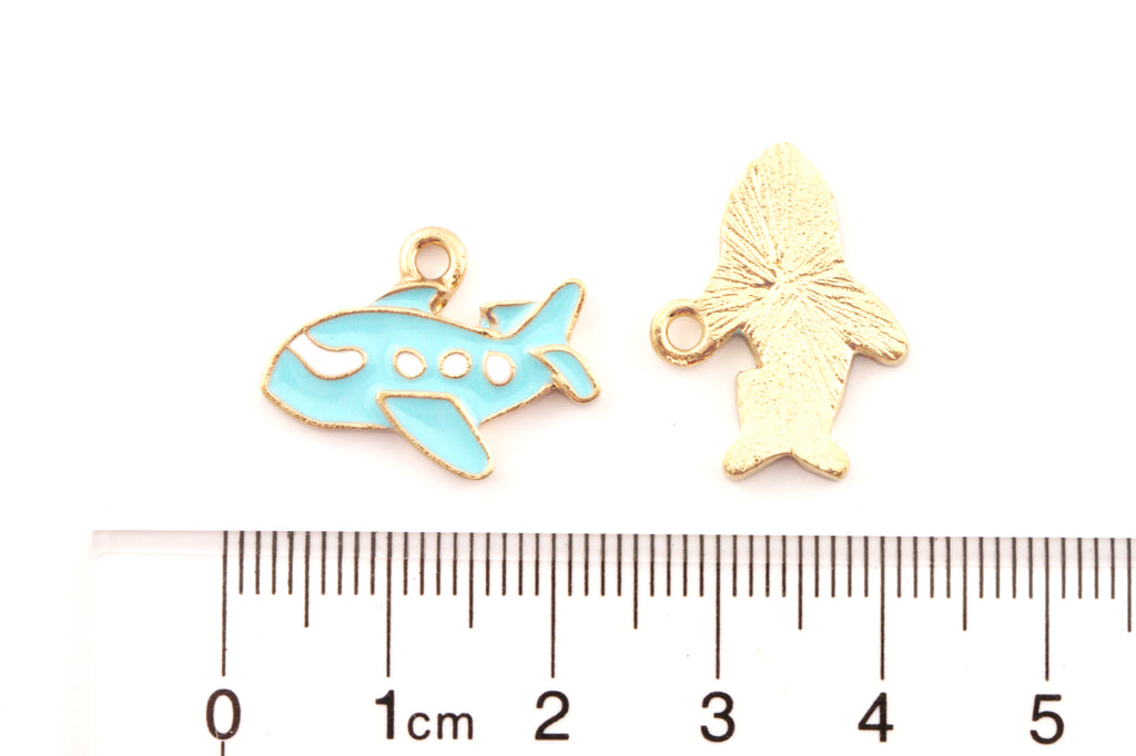 Two airplane  enamel charms on a white background above a cm ruler for scale.