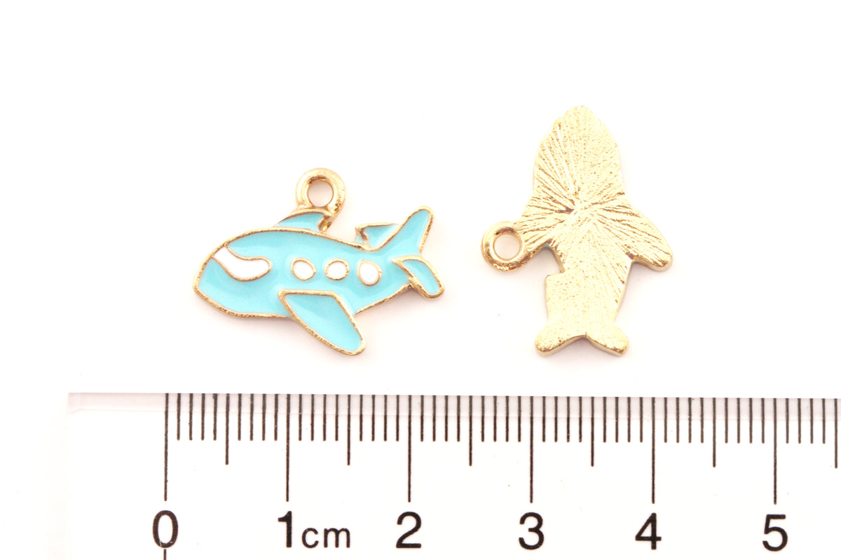 Two airplane  enamel charms on a white background above a cm ruler for scale.