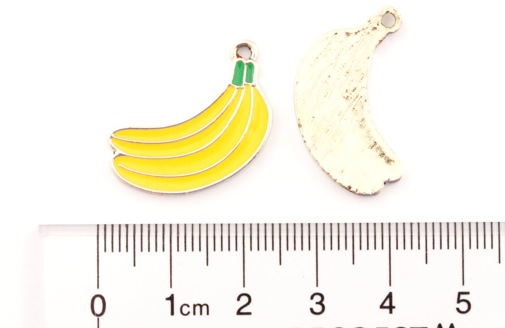 Two banana-shaped jewelry charms shown on a white background with a ruler at the bottom for scale. 