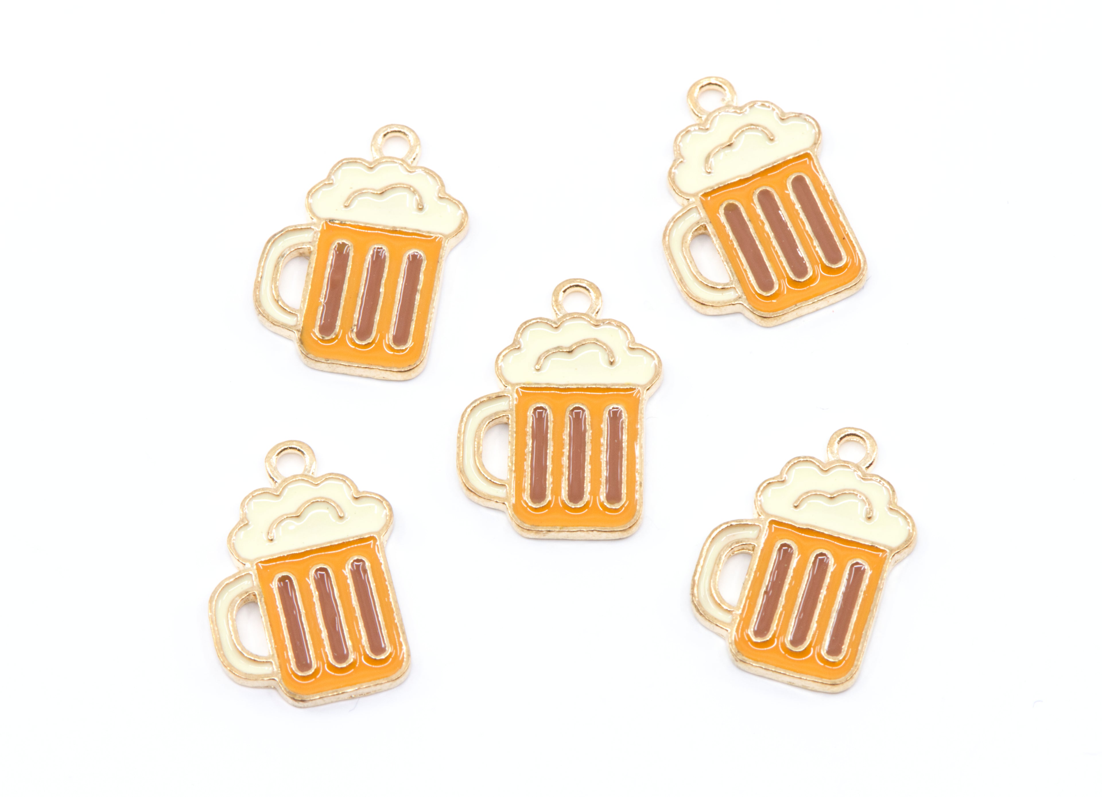 Five small beer mug charms with gold-tone metal outlines and orange enamel, each topped with cream-colored foam, arranged on a plain white background.