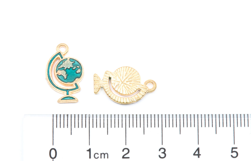 Two blue globe  gold-tone jewelry charms next to a  cm ruler for scale on a white background.