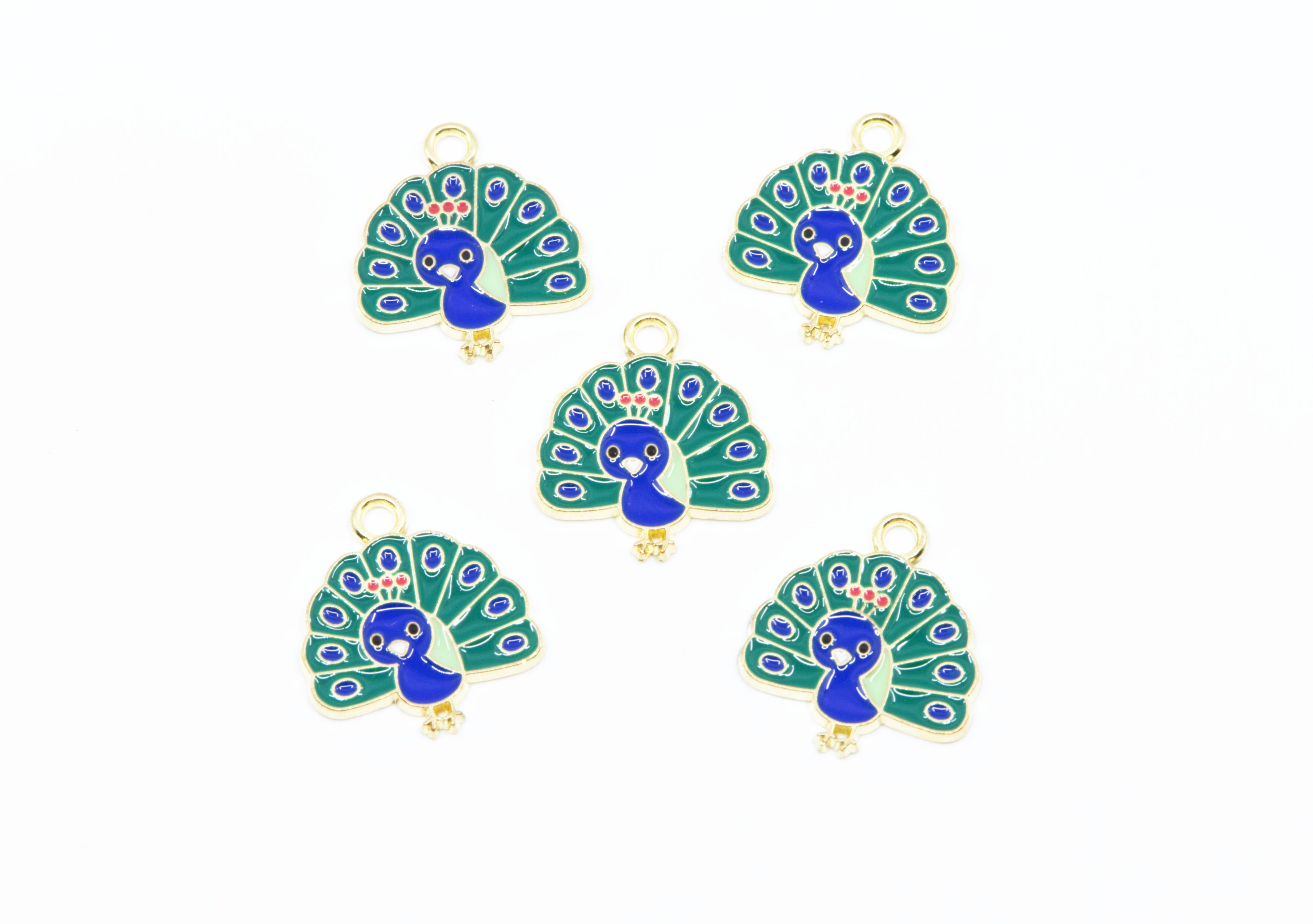 Five peacock-shaped jewelry charms with gold-tone metal borders and loops, featuring blue and green enamel detailing on a white background.